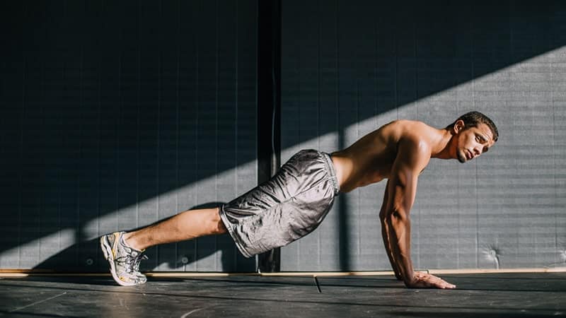 a young man performs a plank exercise in a lower ab workout