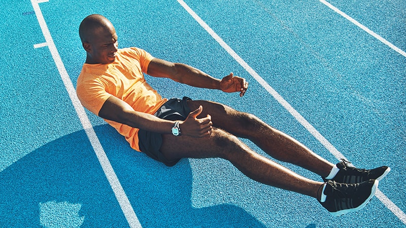 fit young athlete doing crunches on a running track