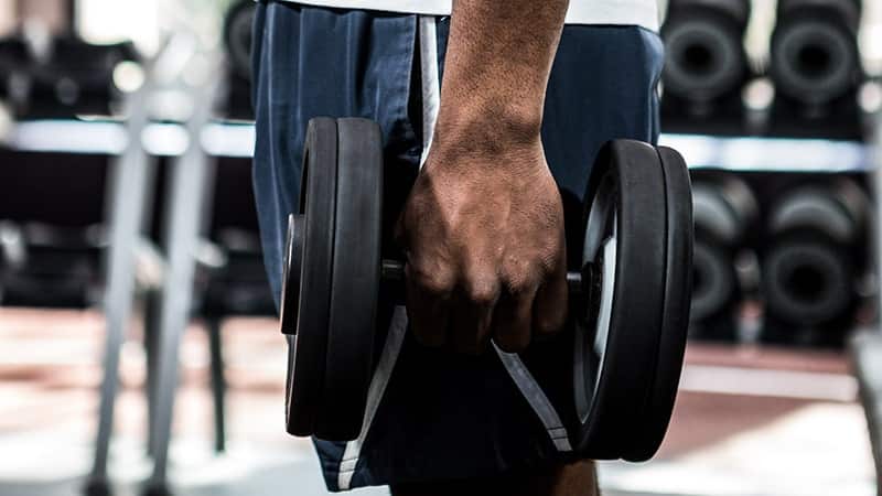 muscular man exercising with dumbbells at gym