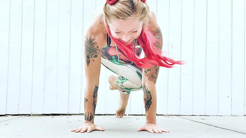 young woman with pink hair doing the plank hop exercise